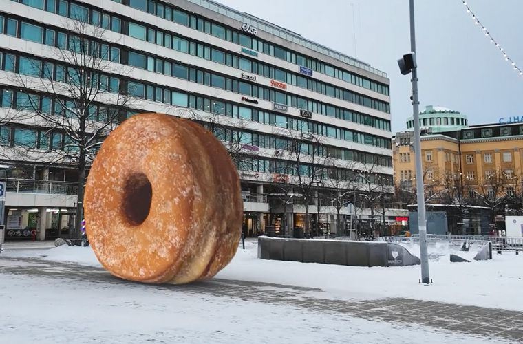 Giant donut sculpture in a snowy urban square with a modern office building in the background.